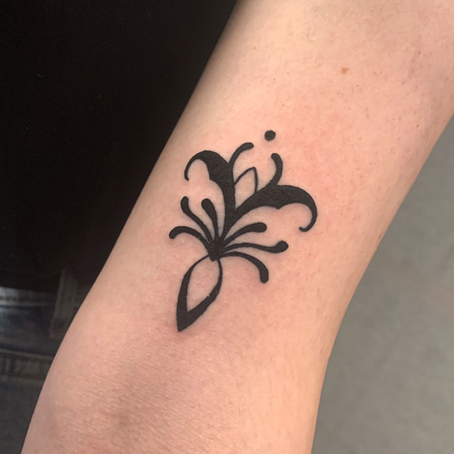 Detailaufnahme eines kleinen floralen Tattoos auf dem Oberarm – Geometrische Einflüsse im Design